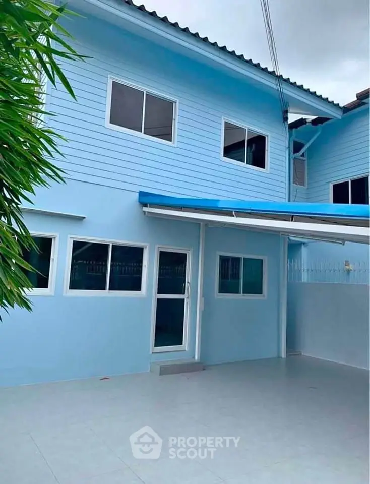 Charming blue two-story house with modern exterior and spacious patio.