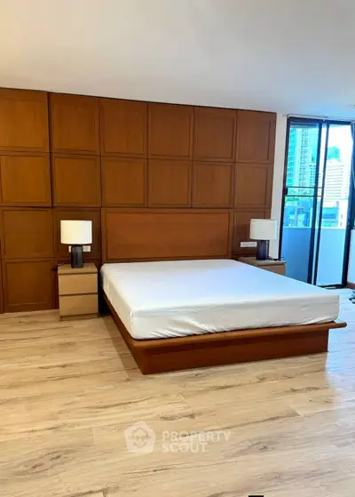 Spacious modern bedroom with wooden accents and city view, featuring a large bed and stylish nightstands.