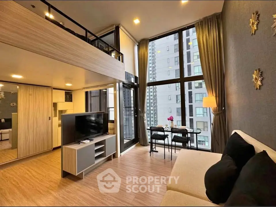Modern loft-style living room with high ceilings and large windows offering city views.