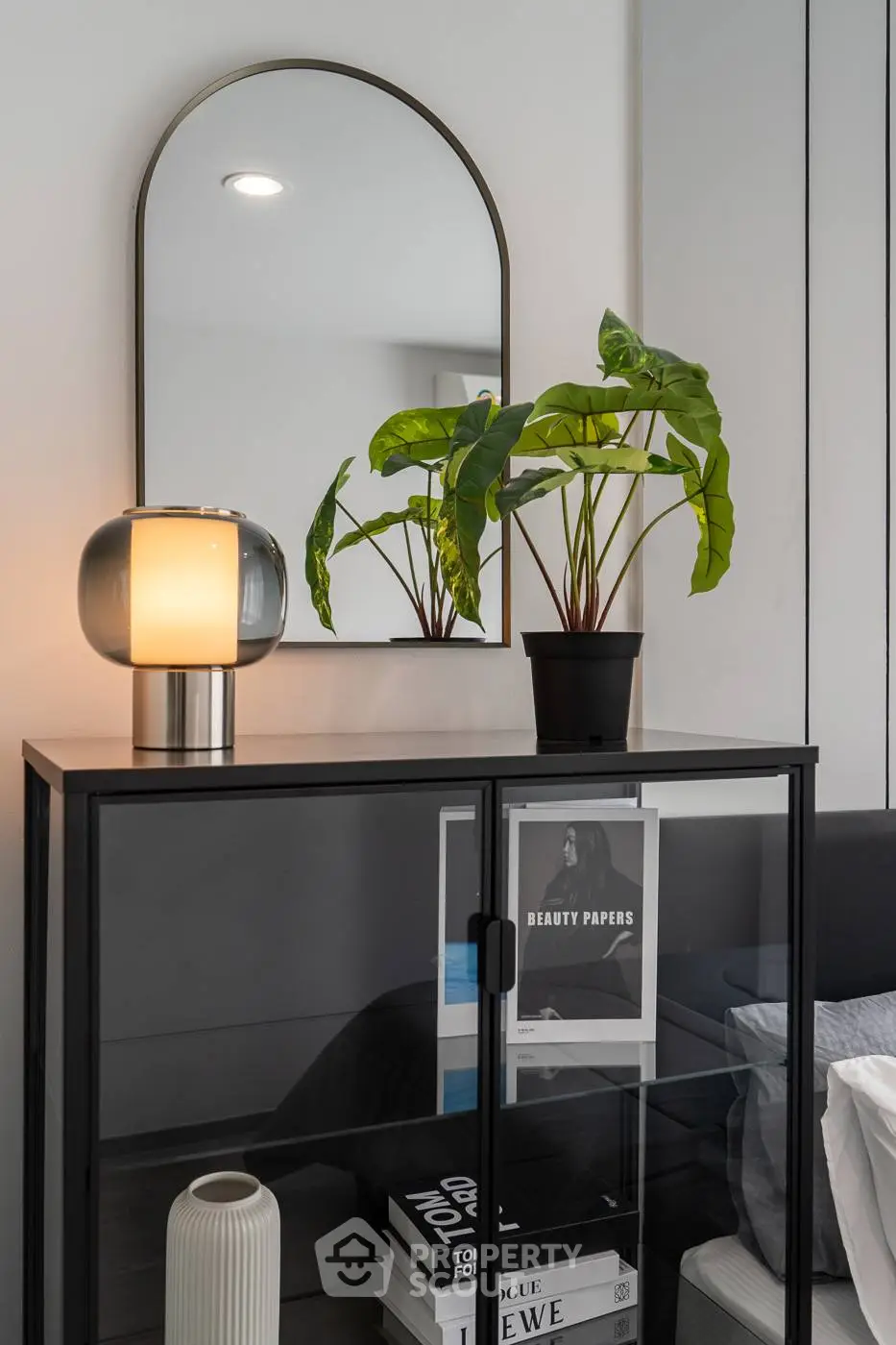 Stylish modern bedroom with glass cabinet, mirror, and potted plant decor.