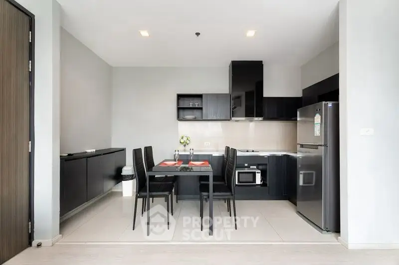 Modern kitchen with sleek black cabinets and dining area in open layout apartment.