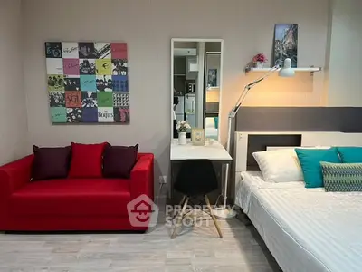 Modern studio apartment with vibrant red sofa and cozy bed setup.
