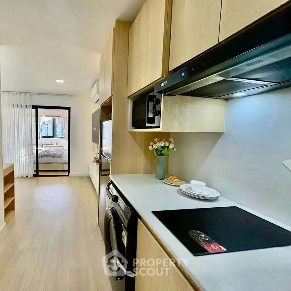 Modern kitchen with sleek appliances and open layout leading to a cozy bedroom.
