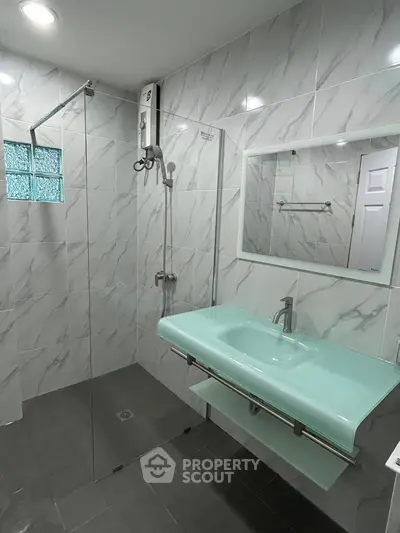 Modern bathroom with glass shower and sleek green sink