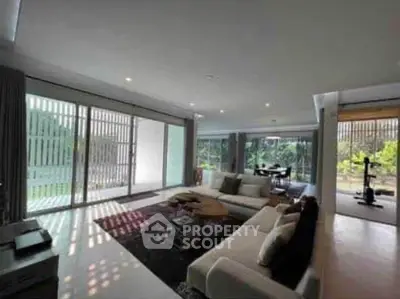 Spacious modern living room with large windows and garden view, perfect for relaxation and entertaining.
