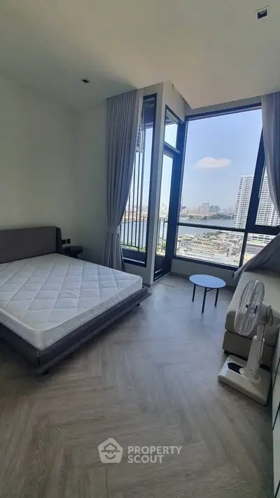 Spacious bedroom with large windows offering stunning city views, modern furnishings, and elegant decor.