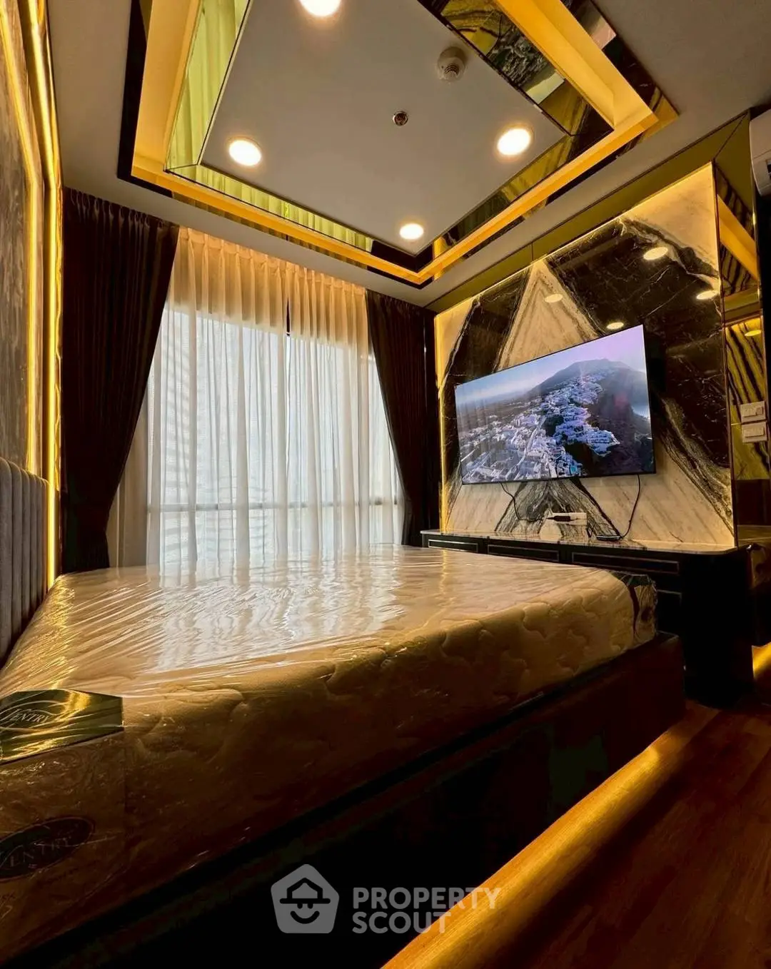 Luxurious bedroom with modern decor and mounted TV, featuring elegant lighting and floor-to-ceiling windows.