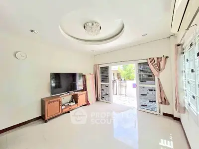 Bright living room with modern TV setup and access to outdoor patio, featuring elegant ceiling light.