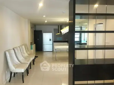 Modern open-plan kitchen with sleek design and dining area, featuring contemporary chairs and bright lighting.