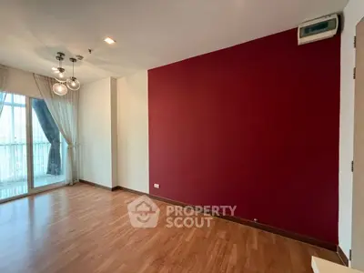 Spacious empty living room with red accent wall and large window view.