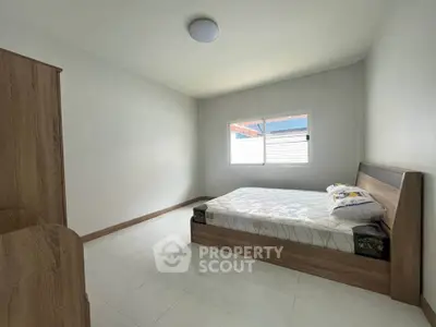 Spacious minimalist bedroom with natural light and modern wooden furniture.