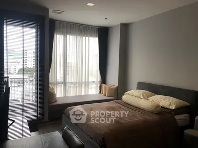 Modern bedroom with large windows and cozy seating area, perfect for relaxation and comfort.