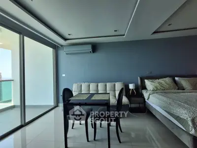 Modern studio apartment with sleek design, featuring a cozy bed, stylish dining area, and large balcony access.