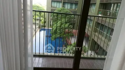 Modern apartment balcony with pool view and lush greenery