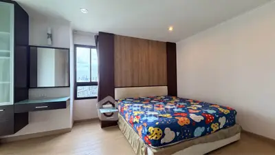Spacious bedroom with city view and modern furnishings in a high-rise apartment.