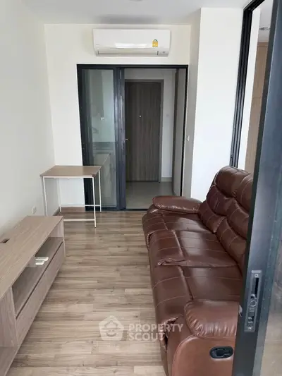 Modern living room with leather sofa and wooden flooring in a cozy apartment.