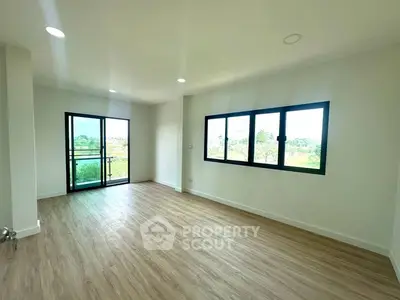Spacious living room with large windows and balcony access, offering a serene view.