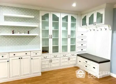 Elegant white storage room with built-in cabinets and seating area