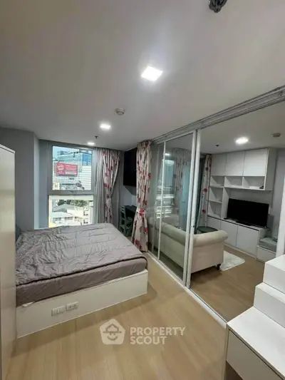 Modern studio apartment with separate living area and city view, featuring sleek design and ample natural light.