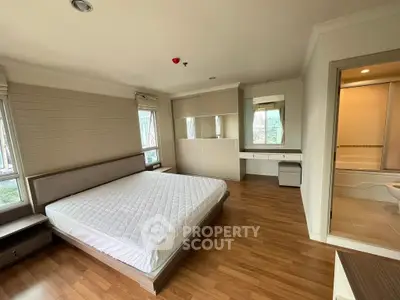 Spacious bedroom with wooden flooring and ensuite bathroom in modern apartment