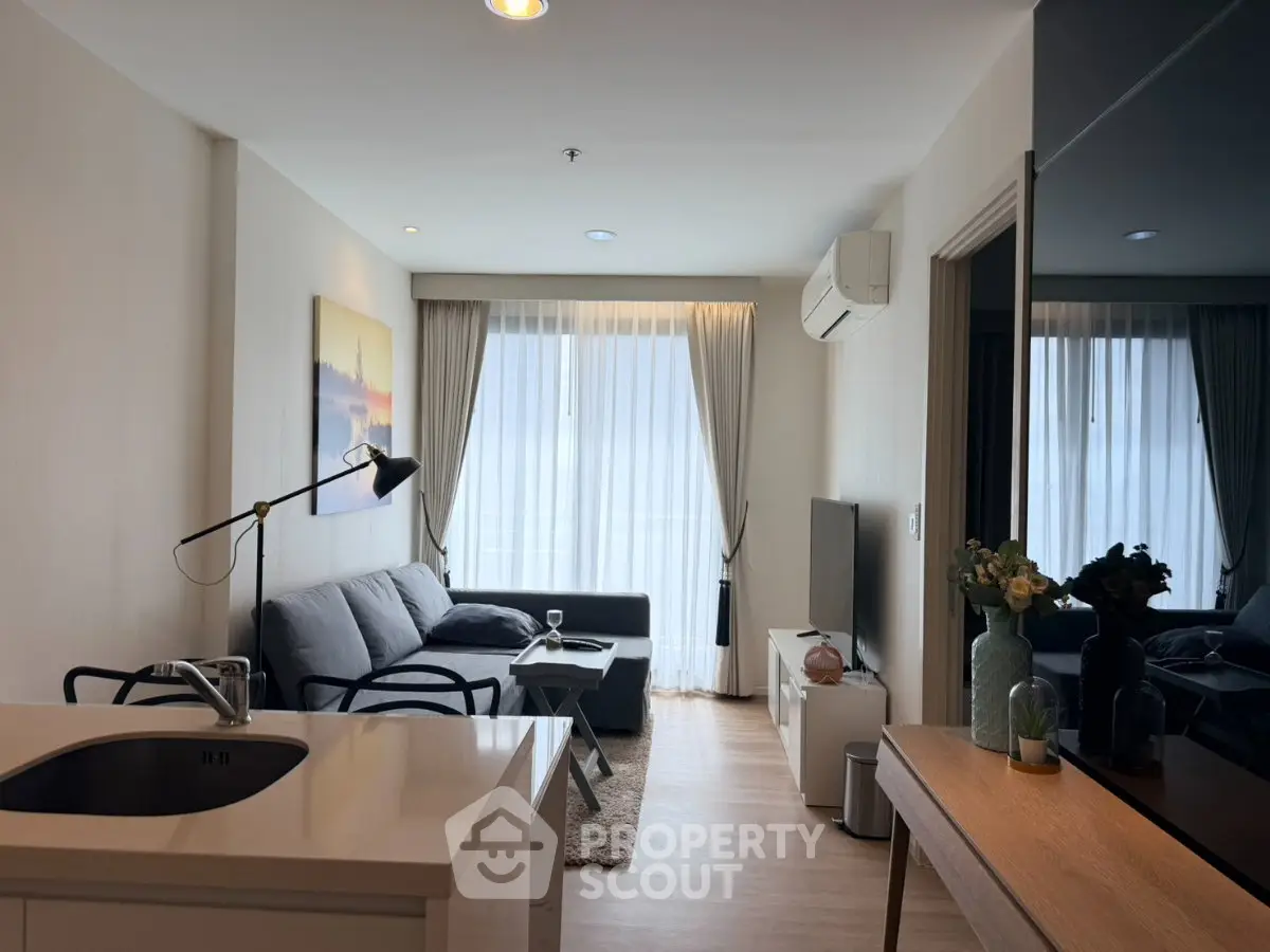 Modern living room with cozy sofa, stylish decor, and natural light from large windows.