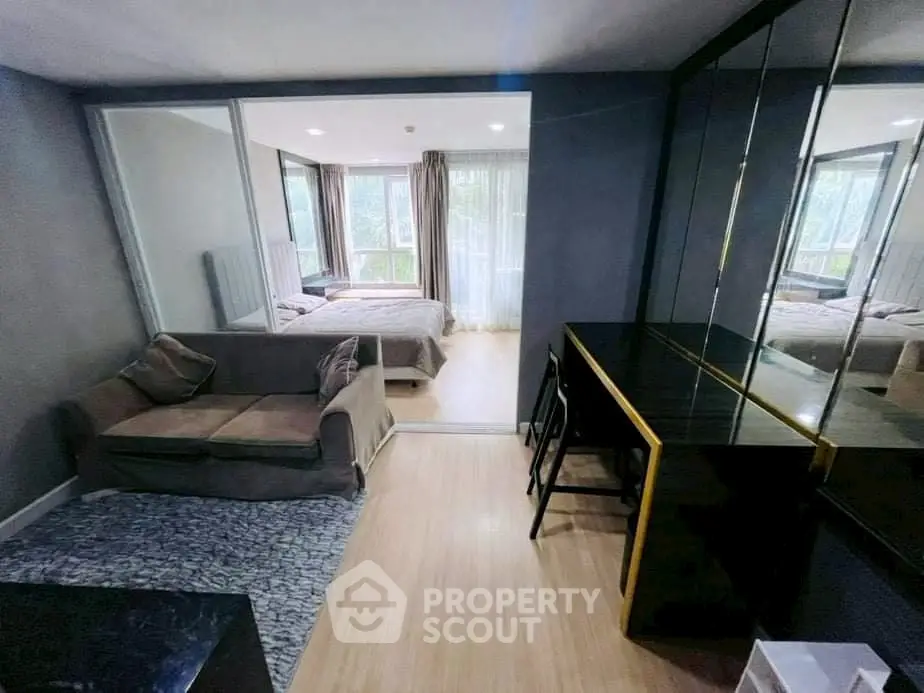 Modern studio apartment with cozy living area and bedroom, featuring sleek design and ample natural light.