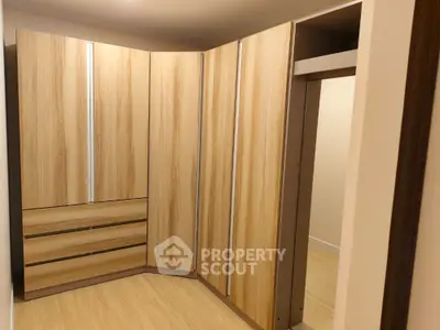 Spacious walk-in closet with modern wooden cabinetry and ample storage space
