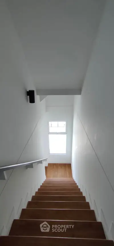 Modern staircase with sleek wooden steps and a skylight, offering a bright and airy ambiance.