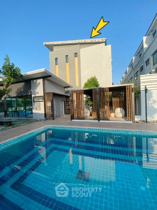 Modern residential building with pool and stylish wooden accents under clear blue sky.