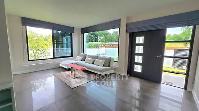 Spacious modern living room with large windows and stylish furniture, offering a bright and inviting atmosphere.