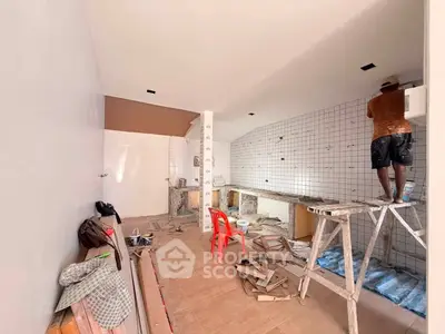 Under-construction kitchen with tiled walls and red chair, showcasing renovation progress.