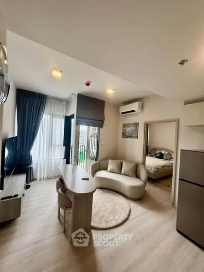 Modern open-plan living room with stylish furniture and natural light, featuring a cozy bedroom view.