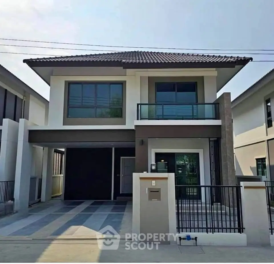 Modern two-story house with sleek design and spacious driveway in a suburban neighborhood.