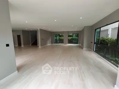 Spacious open-plan living room with large windows and garden view, perfect for modern family living.