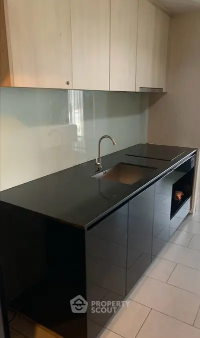 Modern kitchen with sleek black countertops and minimalist cabinetry design.