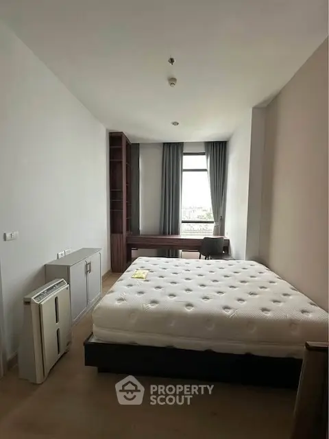 Spacious bedroom with large window and modern furnishings in a stylish apartment.