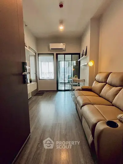 Modern living room with sleek leather sofa and city view balcony, perfect for urban living.