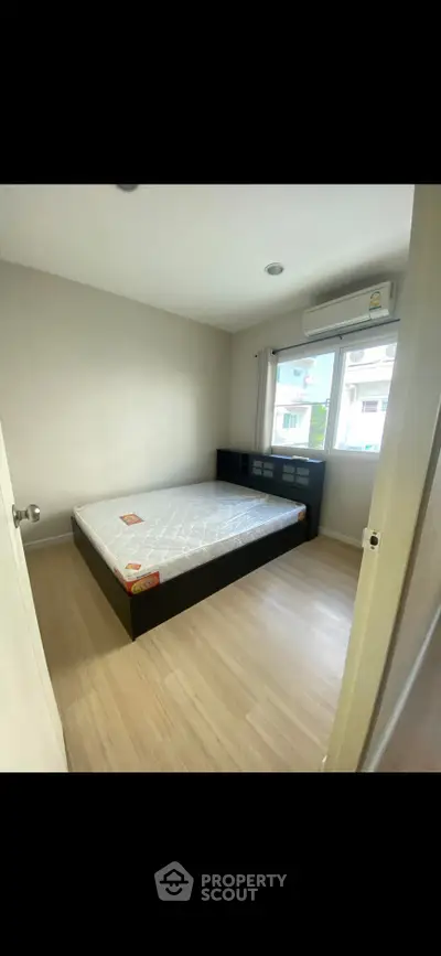 Spacious bedroom with large window and modern furnishings in a bright apartment.