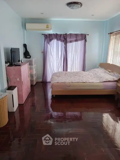 Spacious bedroom with polished wooden floors and natural light