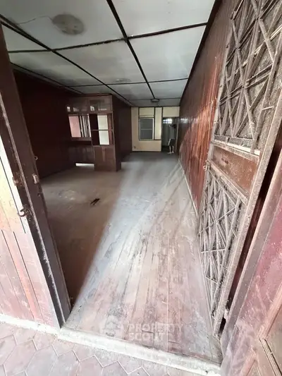 Spacious wooden interior with potential for renovation, featuring vintage charm and ample natural light.