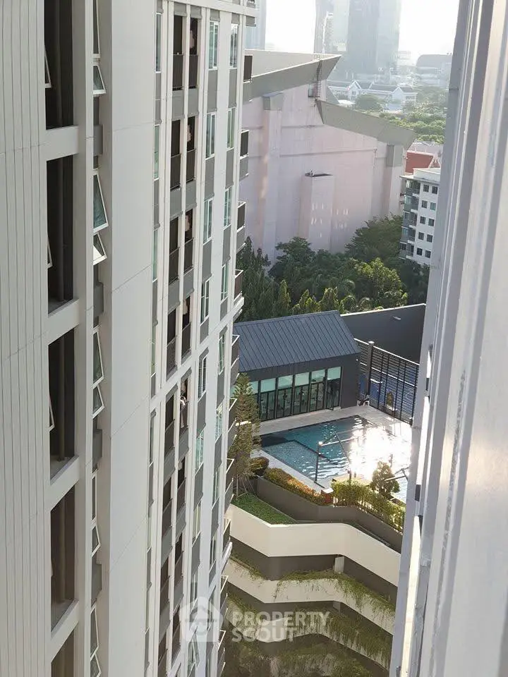 Stunning high-rise building view with pool and lush greenery in urban setting.