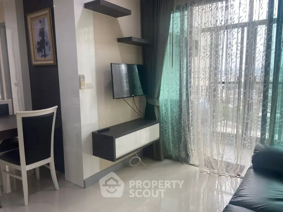 Modern living room with sleek TV setup and large windows offering natural light and city views.