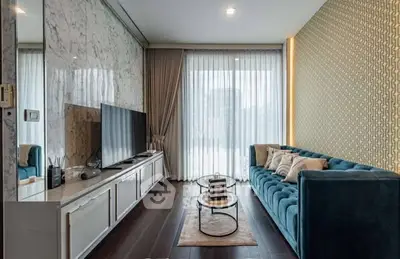 Stylish modern living room with elegant decor and large TV, featuring a plush blue sofa and floor-to-ceiling windows.