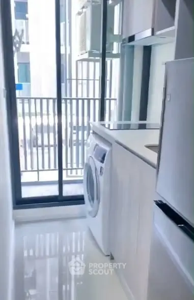 Modern kitchen with washing machine and balcony view in sleek apartment