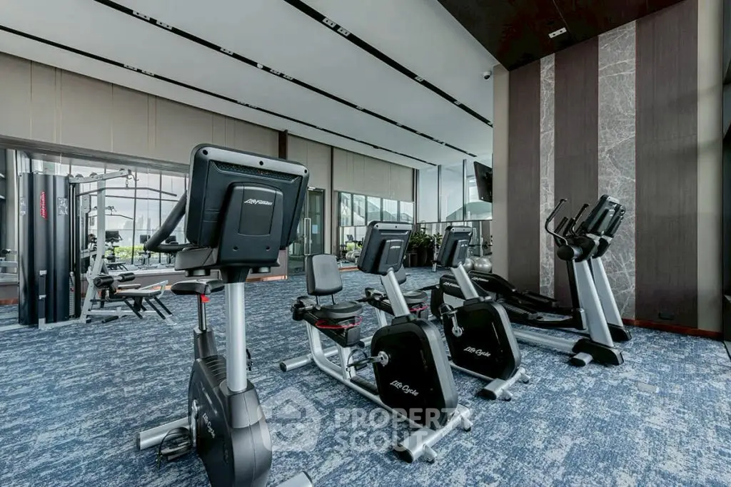 Spacious modern gym with state-of-the-art exercise equipment and large windows for natural light.