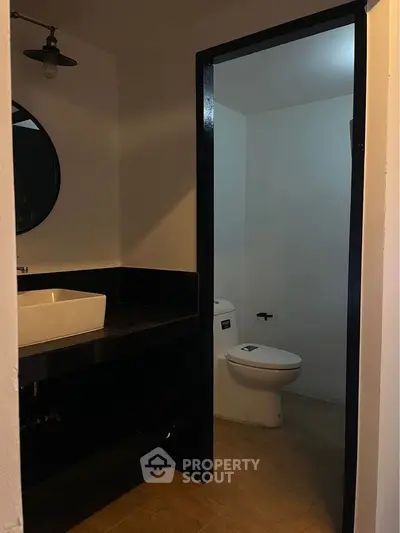 Modern bathroom with sleek black accents and round mirror