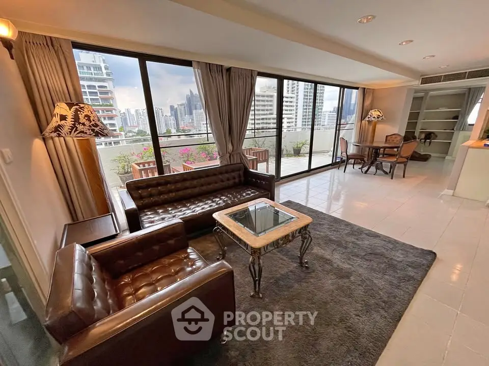 Spacious living room with large windows and city view, featuring elegant leather furniture and a cozy atmosphere.