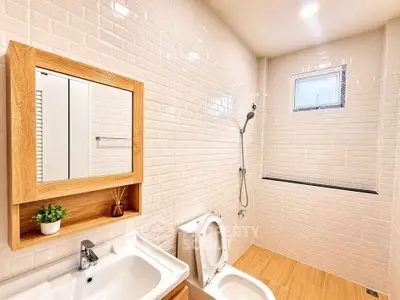 Modern bathroom with sleek white tiles and wooden accents, featuring a shower and vanity.