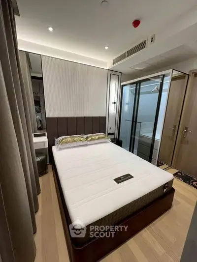 Modern bedroom with stylish decor and glass partition, featuring a comfortable bed and elegant lighting.