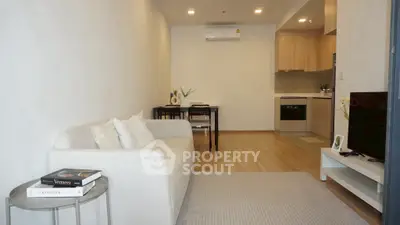 Modern living room with cozy sofa and open kitchen layout in stylish apartment.